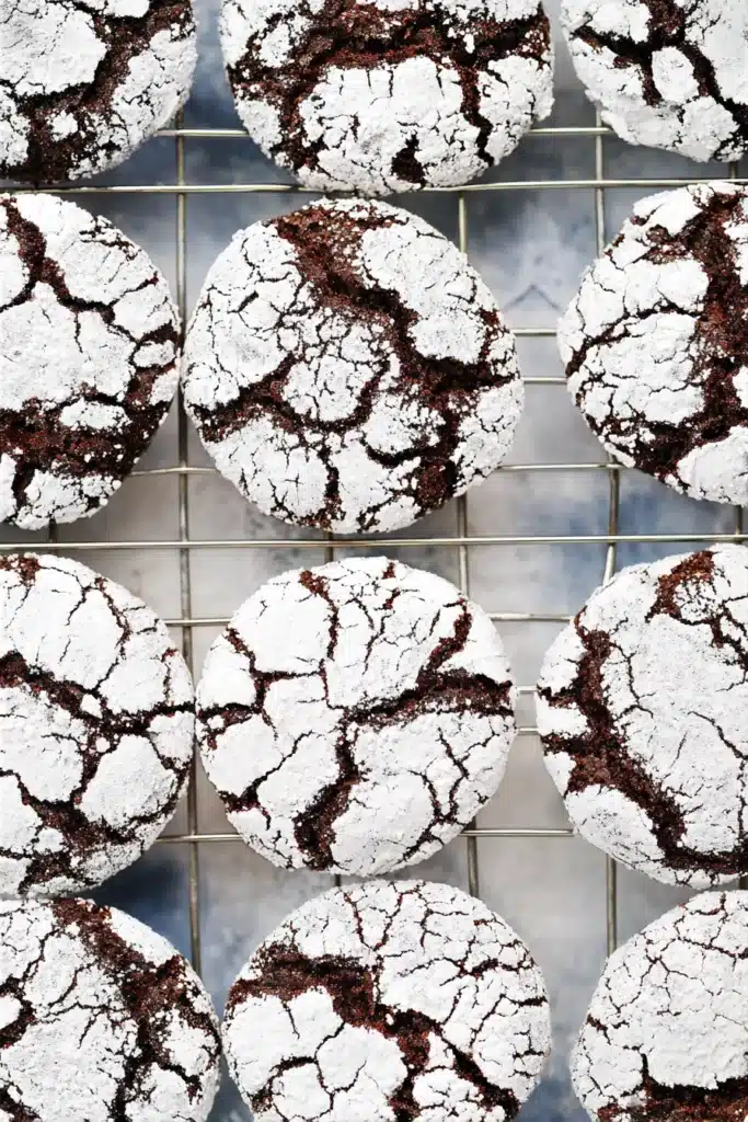 Gluten-free chocolate crinkle cookies coated in powdered sugar on cooling rack