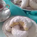 Crescent-shaped Greek cookies with powdered sugar on a plate
