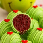 Green Grinch Oreo Balls with red hearts and red velvet filling on white plate