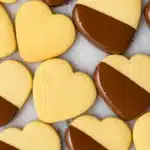 Heart-shaped shortbread cookies dipped in dark chocolate on marble surface