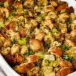 Golden homemade bread stuffing with celery and herbs in white baking dish