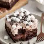 Moist hot cocoa poke cake slice topped with marshmallows and chocolate chips
