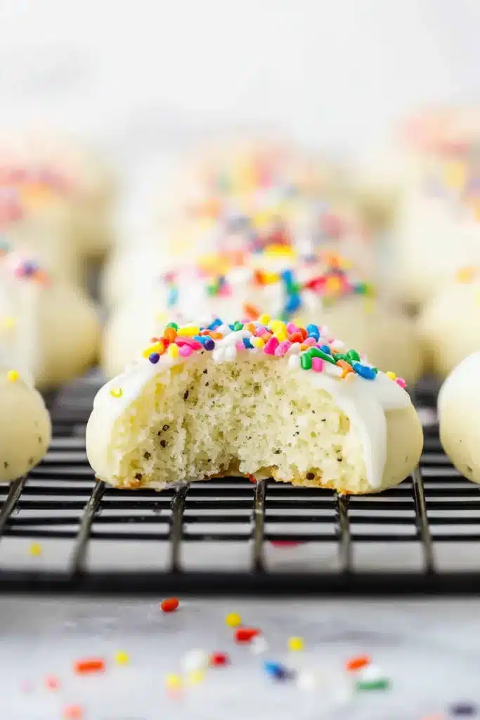 Easy Homemade Anise Cookies | Perfect Christmas Treats 9 Close-up of a colorful sprinkle-topped iced cookie with a bite taken out.