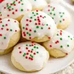 Soft Italian Christmas cookies with white icing and colorful sprinkles on a plate