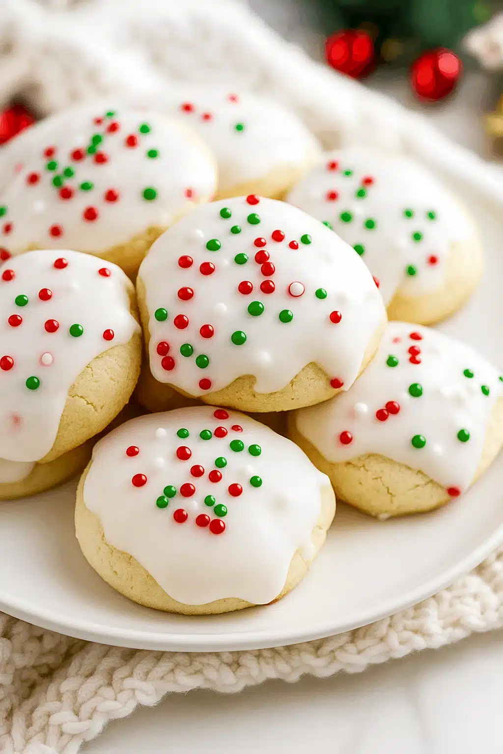 Soft Italian Christmas cookies with white icing and colorful sprinkles on a plate