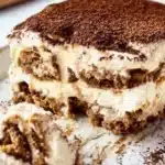 Slice of gingerbread tiramisu with creamy layers and cocoa topping on a white plate