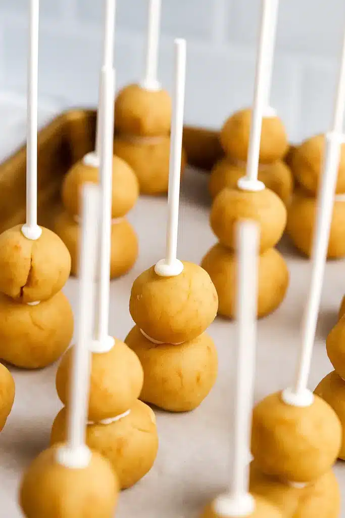 Snowman cake pops being shaped on sticks before coating