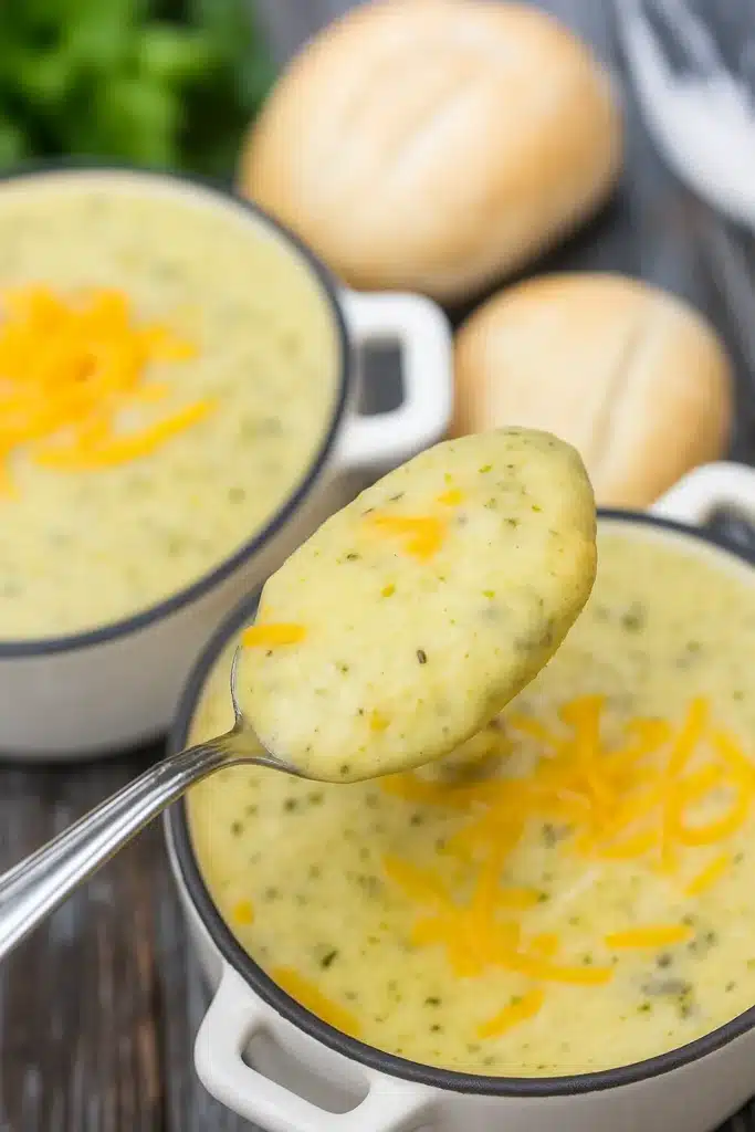 Spoon lifting creamy zucchini soup topped with cheddar cheese