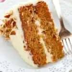 The BEST Carrot Cake slice with cream cheese frosting and chopped pecans