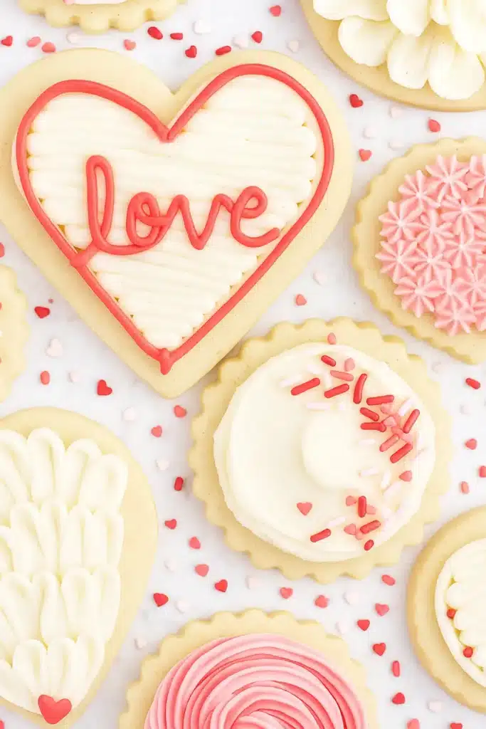 Heart-shaped buttercream sugar cookie with pink and white frosting and sprinkles