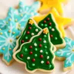 Vegan sugar cookies decorated with glossy icing shaped like trees, stars, and snowflakes.