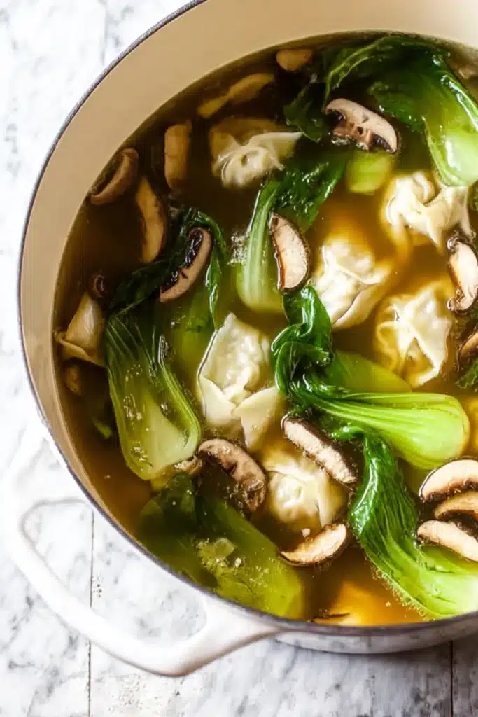 Wonton Soup Recipe with Quick Flavor and Comfort 6 Pot of homemade Wonton Soup Recipe with mushrooms, bok choy, and golden broth
