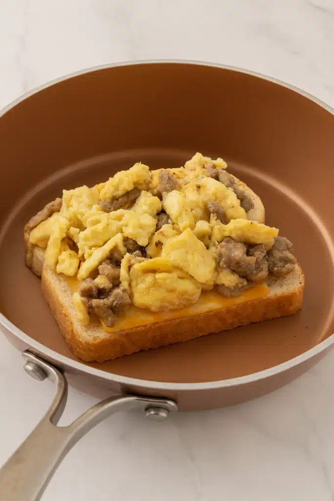 Open-faced breakfast grilled cheese with eggs, sausage, and cheese on bread