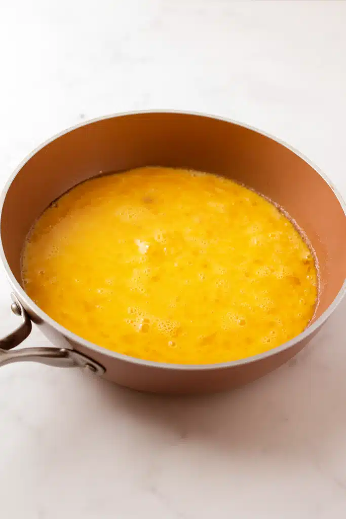 Golden beaten eggs cooking in copper skillet after scrambling step