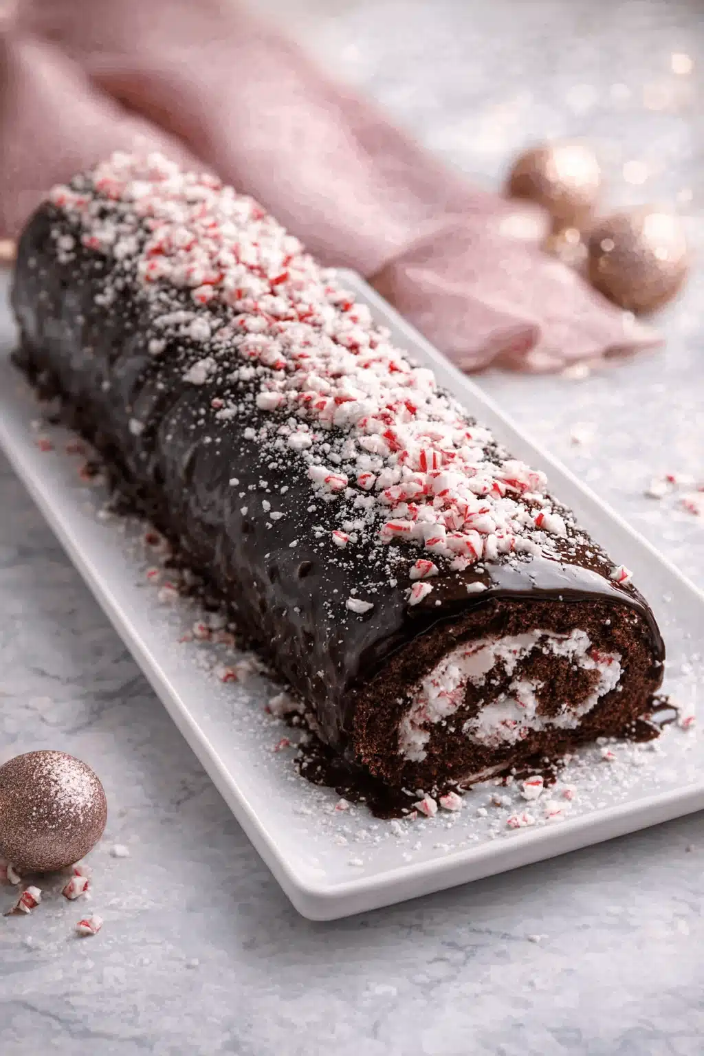 Best Christmas Peppermint Roll Cake topped with crushed peppermint on white plate