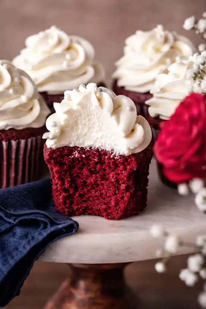 Red Velvet Cupcakes | Amazing Creamy Frosting Recipe 8 Bitten red velvet cupcake with cream cheese frosting and blue napkin cloth