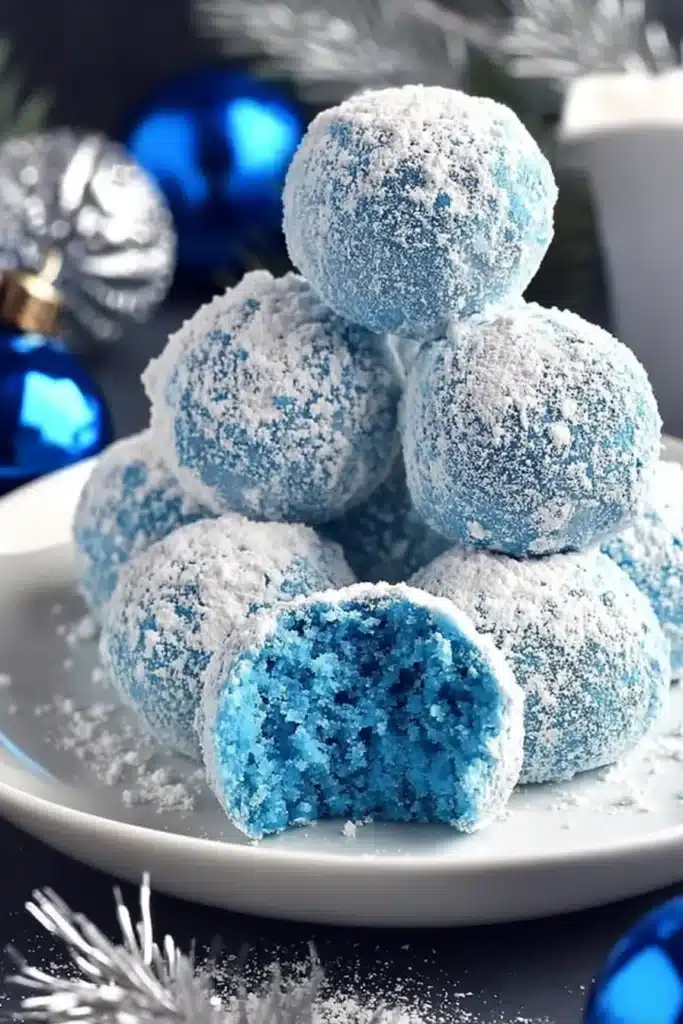 Blue Christmas truffles dusted with powdered sugar on a white plate
