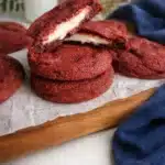 Cheesecake stuffed red velvet cookies stacked on a wooden board