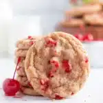 Soft cherry almond cookies with red cherry pieces on white marble surface