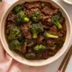 Easy Chinese beef and broccoli in glossy brown sauce served with rice on a soft pastel background