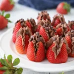 Chocolate cheesecake stuffed strawberries on a white-gray table with creamy chocolate filling