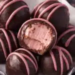 Close-up of chocolate raspberry truffles with pink drizzle and creamy raspberry filling