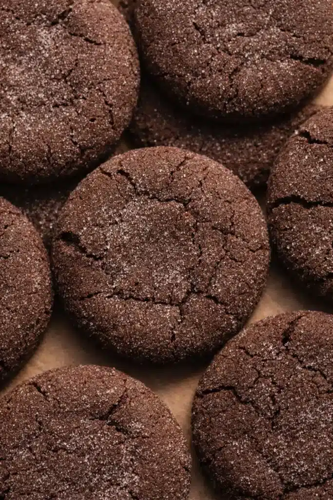 Chocolate sugar cookies with crackled tops on brown parchment background