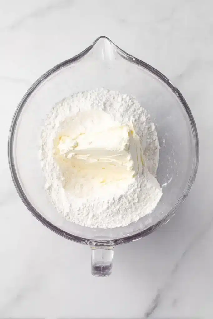 Christmas Cookie Lush Recipe | Easy, Festive & Delicious 25 Cream cheese and powdered sugar in a glass bowl for Christmas Cookie Lush