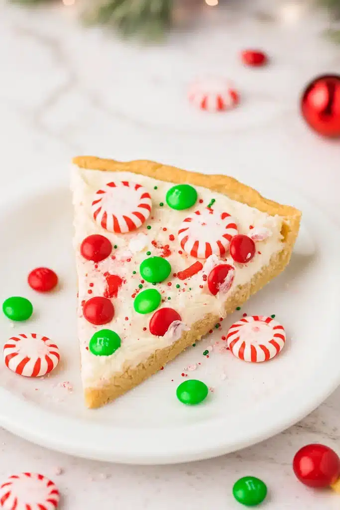 Christmas cookie pizza slice with frosting, peppermint, and colorful candies