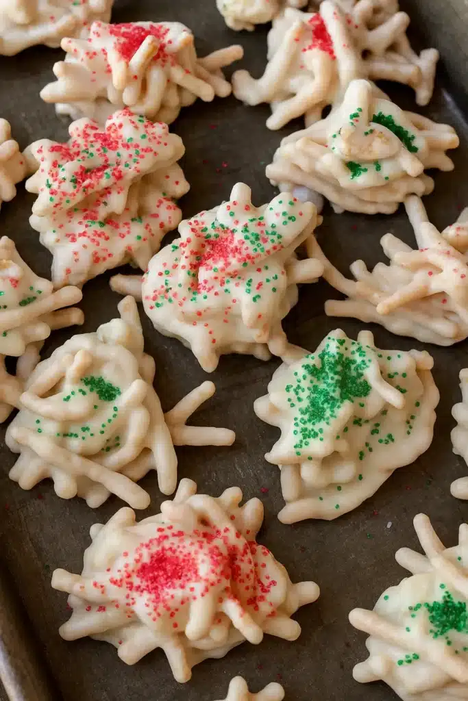 Christmas Haystacks coated in white chocolate with red and green sprinkles on a gray tray