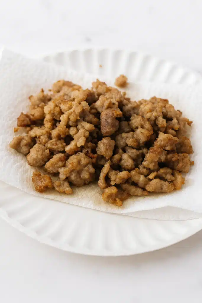 Cooked chicken sausage crumbles on paper towel for breakfast grilled cheese