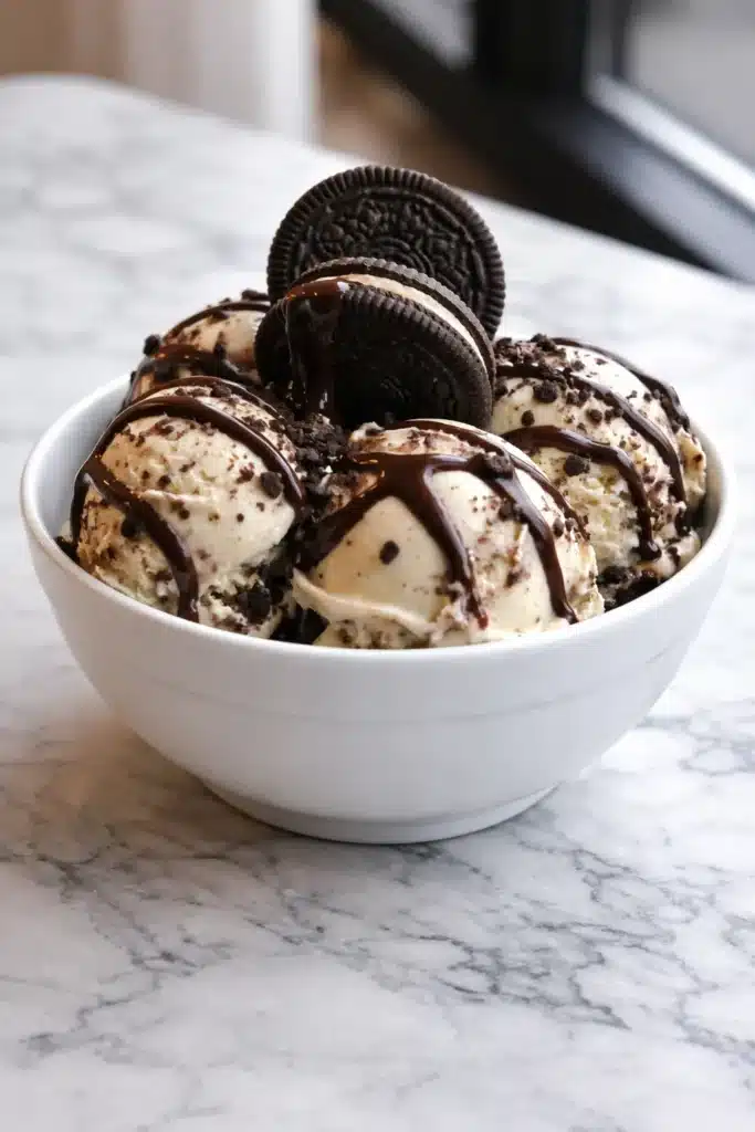 Cookies and cream ice cream with chocolate syrup and Oreo cookies in a white bowl