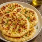 Freshly cooked cottage cheese flatbreads brushed with olive oil and herbs on a wooden board