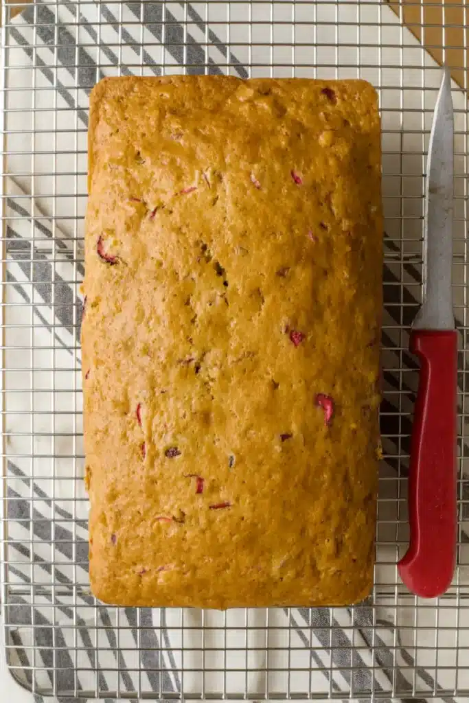 Cranberry Nut Bread Recipe | Sweet, Tart & Easy Loaf 8 Cranberry nut bread loaf cooling on wire rack with knife