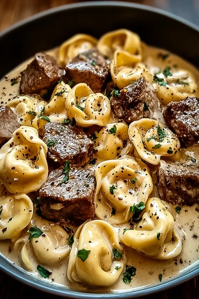 Garlic steak tortellini in creamy parmesan sauce in white bowl