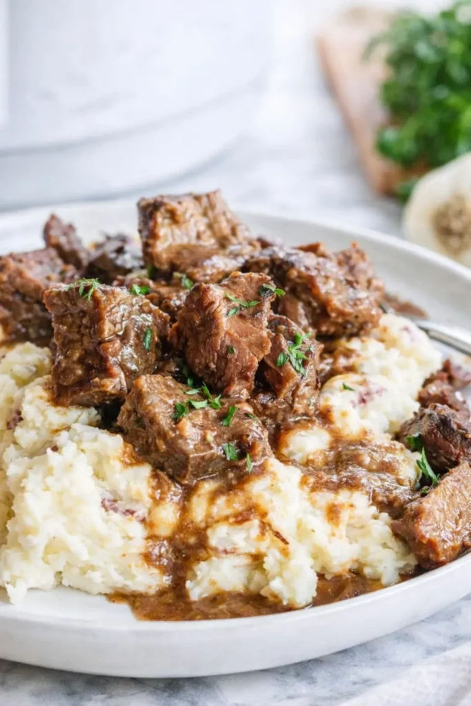 Crockpot steak bites with gravy over mashed potatoes
