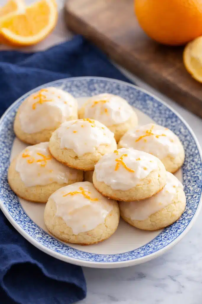 Easy Christmas Cookies with Orange Juice | Simple & Delicious 6 Orange-glazed Christmas cookies on white plate with blue rim on marble surface