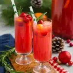 Festive Christmas punch with cranberries, orange slices, and rosemary in tall glasses
