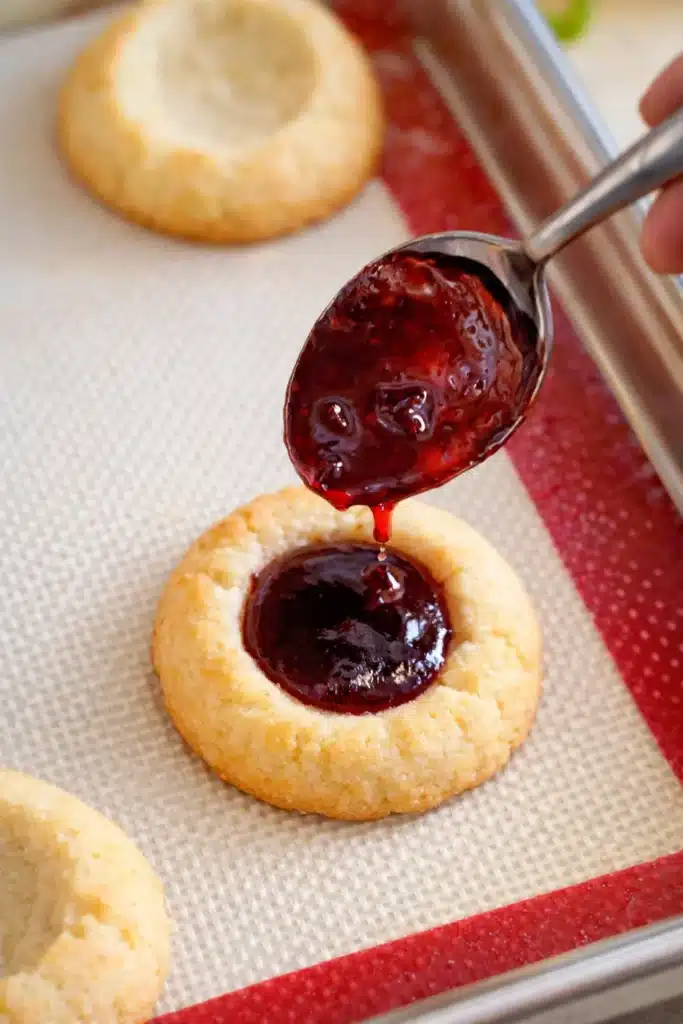 Raspberry Thumbprint Cookies with Icing – Simple Joy 11 Spooning glossy raspberry jam into thumbprint cookies