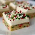 Christmas cookie bars topped with white frosting and red and green sprinkles