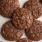 Fudgy chocolate brownie cookies with crinkled tops and chewy centers on a light surface