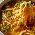 Bowl of ginger scallion chicken noodle soup with noodles, scallions, and chili oil