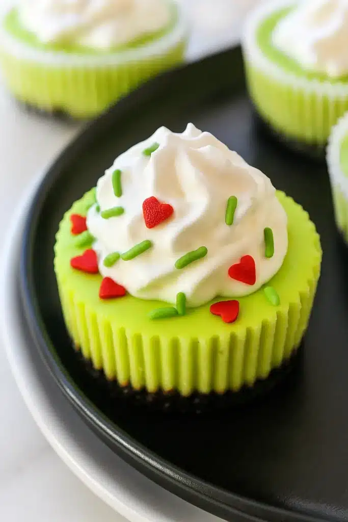 Grinch Mini Cheesecakes – Festive, Fun & Easy Dessert 7 Grinch mini cheesecake with whipped cream and festive red and green sprinkles