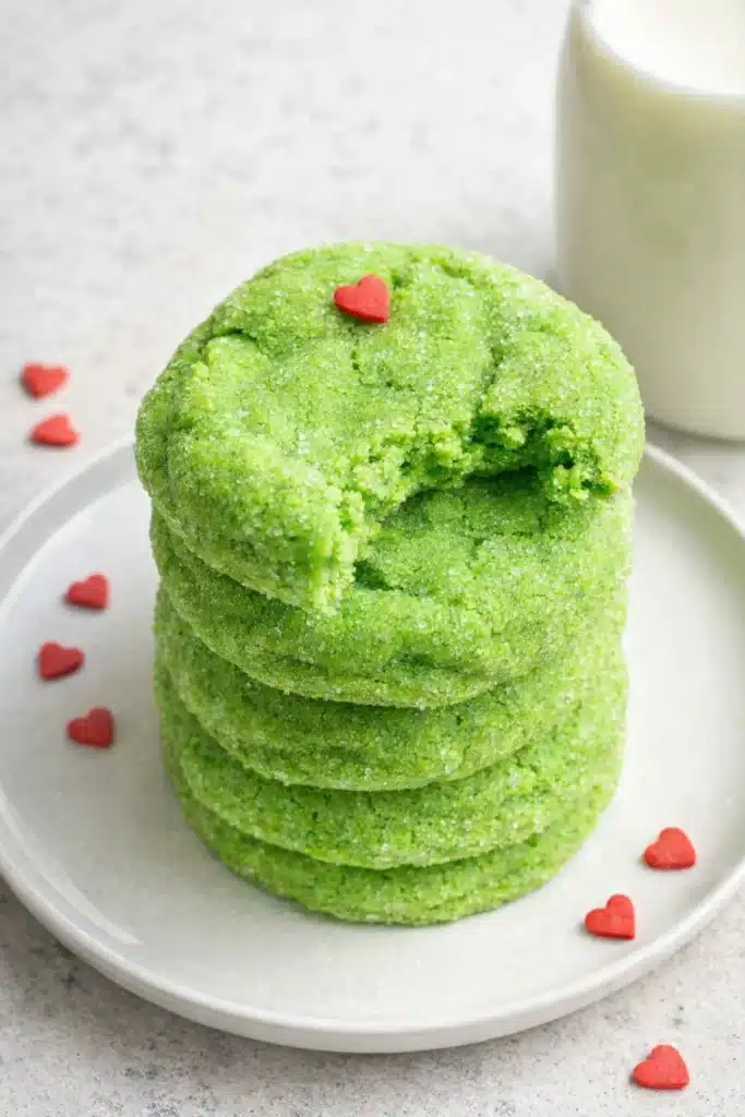 Stack of Grinch sugar cookies with red hearts on white plate