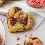 Heart shaped chocolate chip cookies with melted chocolate and pink sprinkles