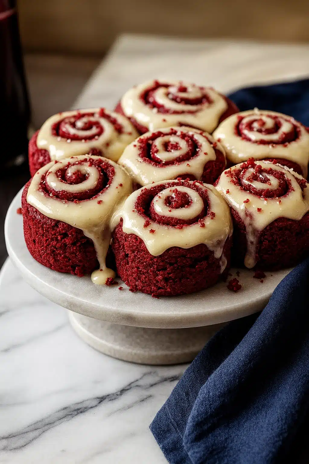 Heavenly Red Velvet Cinnamon Rolls on a white ceramic plate with cream cheese frosting