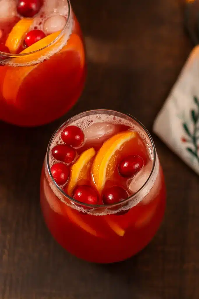 Holiday Punch Recipe | Easy, Festive & Delicious Drink 6 Two glasses of holiday punch with orange slices and cranberries on brown table