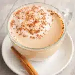 Homemade Vanilla Cinnamon Milk Tea in glass cup with cinnamon stick on saucer
