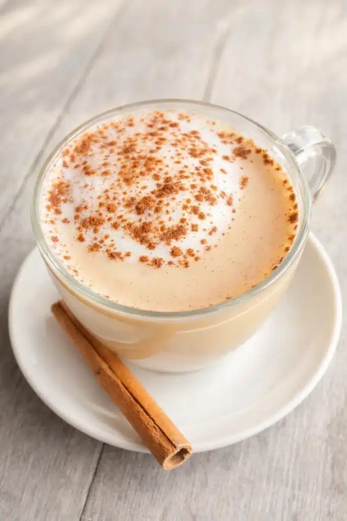 Homemade Vanilla Cinnamon Milk Tea in glass cup with cinnamon stick on saucer