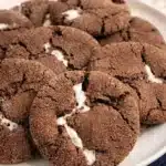 Hot chocolate cookies with gooey marshmallow centers on a white plate